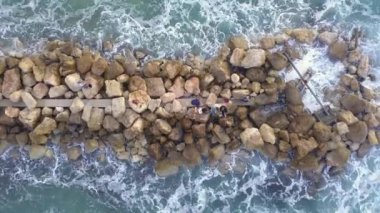 Dalgakıranın üzerinde duran balıkçıların hava manzarası.