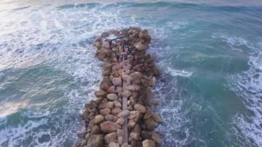 Dalgakıranın üzerinde duran balıkçıların hava manzarası.