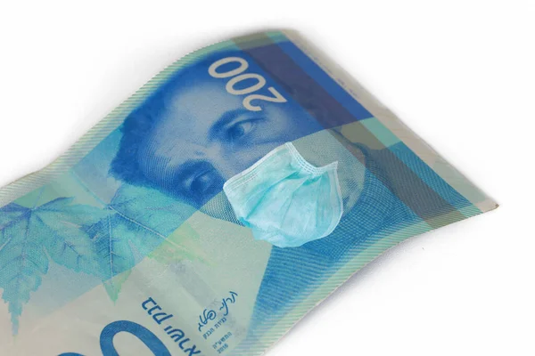Yüz maskeli 200 NIS para faturası. COVID-19 ISRAEL 'i etkiliyor. Coronavirus Krizi ve Finans Konsepti.