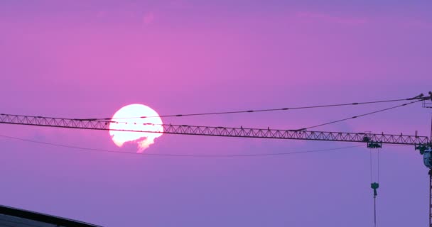 夕阳西下,粉红的天空,背景上的建筑起重机. — 图库视频影像
