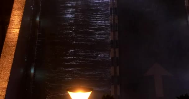 Autoscheinwerfer beleuchten eine dunkle Straße in einer regnerischen Nacht. — Stockvideo