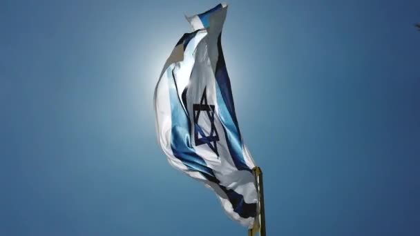 Bandeira de Israel acenando ao vento, Céu e Sol Fundo. Luz solar intensa e brilho, olhando para uma perspectiva de pólo de bandeira . — Vídeo de Stock