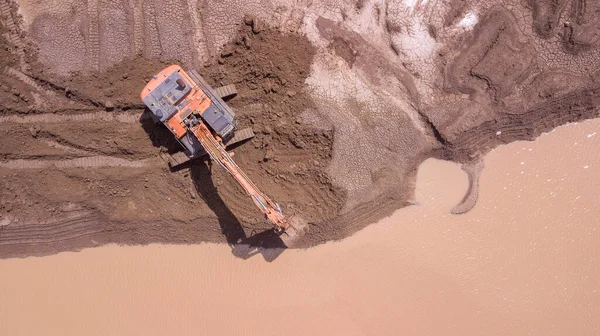 Grävmaskinen är i drift i blöt jord på en ny byggarbetsplats. Konstruktion av översvämningsbarriärer. — Stockfoto