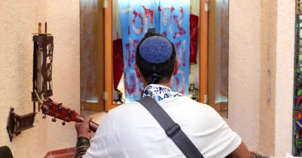 Rabbin du mouvement de réforme juive est enveloppé dans un Tallit, prie, et joue de la guitare devant la Torah ARK. — Video