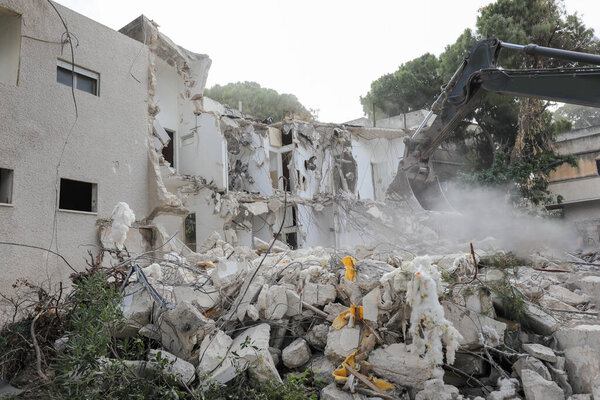 Экскаватор сносит казармы для нового строительства. 