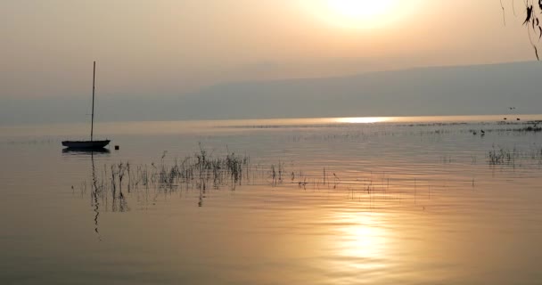 Matahari terbit di atas danau. Perahu mengambang di air yang tenang di bawah matahari terbenam yang menakjubkan. — Stok Video
