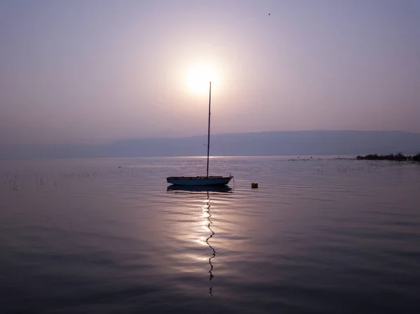 Napkelte a tó felett. Csónak lebeg a nyugodt vízen a csodálatos naplemente alatt. — Stock Fotó