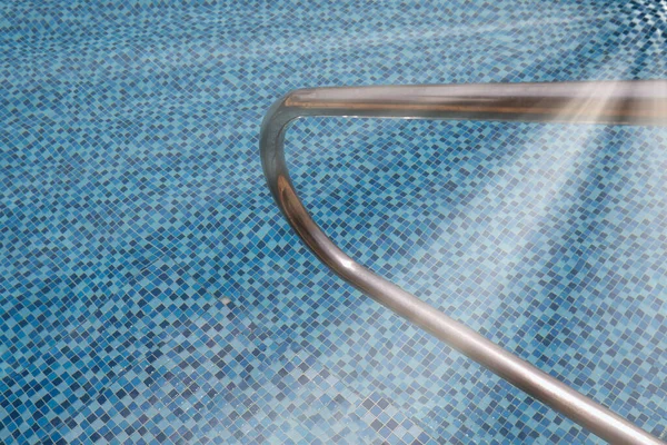 Grab bars ladder in a blue swimming pool.