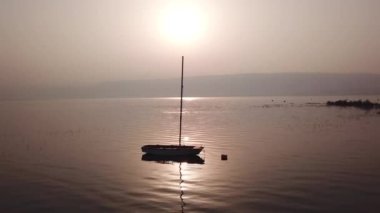 Gölün üzerinde gün doğumu. Gün batımında sakin sularda yüzen bir tekne..