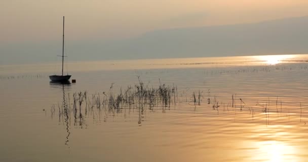 Nascer do sol sobre o lago. Barco flutuando na água calma sob o pôr do sol incrível. — Vídeo de Stock