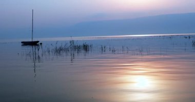 Gölün üzerinde gün doğumu. Sakin sularda yüzen bir tekne İnanılmaz gündoğumu altında.