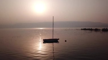 Gölün üzerinde gün doğumu. Gün batımında sakin sularda yüzen bir tekne..