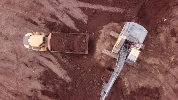 Excavator loading soil on a tipper truck. Earthmoving equipment. Aerial view. — Stock Video