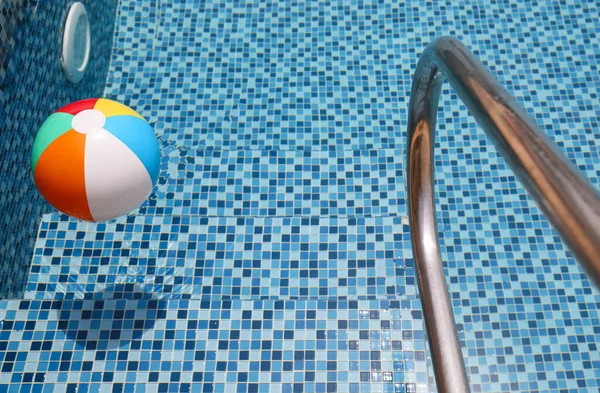 Bola de praia na piscina. Bola inflável colorida que flutua na piscina, conceito das férias do verão. — Fotografia de Stock