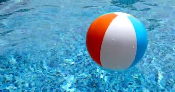 Strandbal in het zwembad. Kleurrijke opblaasbare bal drijvend in zwembad, zomervakantie concept. — Stockvideo