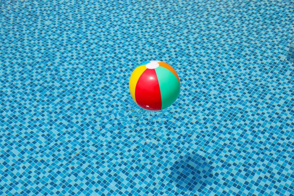 Tengerparti labda a medencében. Színes felfújható labda úszó medence, nyári nyaralás koncepció. — Stock Fotó