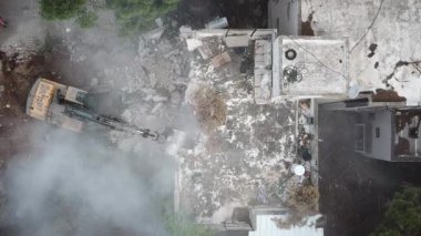 Kazıcı yeni inşaat projesi için barakaları yıkıyor. 