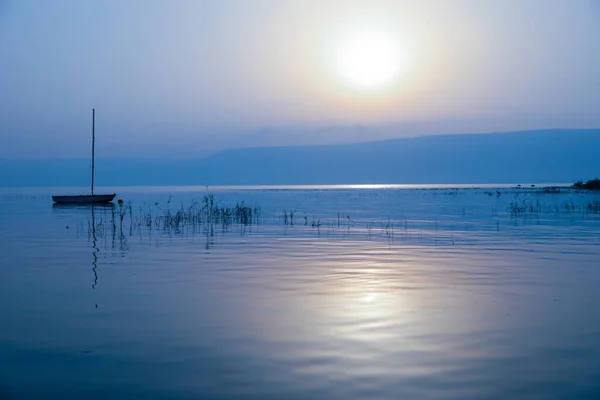 Salida del sol sobre el lago. Barco flotando en el agua tranquila bajo increíble puesta de sol. —  Fotos de Stock