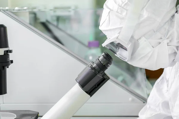 A labor tudósai védőruhát viselnek, mikroszkópokat keresnek, miközben orvosi kutatást végeznek egy tudományos laboratóriumban.. — Stock Fotó
