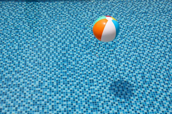 Pelota de playa en la piscina. Bola inflable colorida flotando en la piscina, concepto de vacaciones de verano. — Foto de Stock