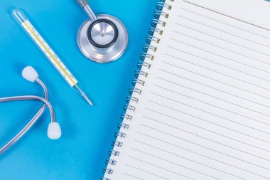 Mavi arka planda boş kağıt ve tıbbi ekipman. Boşluğu kopyala.