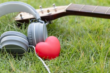 Müziğe bayılırım. Kırmızı kalp, kulaklık, müzik ve gitar klasiği yeşil alanlarda. Yaşamın sesi. Akustik müzik.