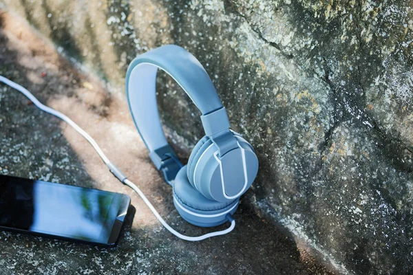 Müzik kulaklığında yaşam tarzı. Cep telefonu açık havada eski beton koltukta..