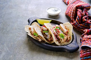 Tavuklu taco, turp ve elma salatası ve ekşi krema soslu yuvarlak buğday tortilla gri beton arka planda oval ahşap bir tabakta. Meksika yemeği.