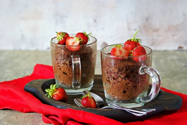 Chocolate muffin in a glass mug, decorated with fresh strawberries and mint leaves. Baking in a mug.