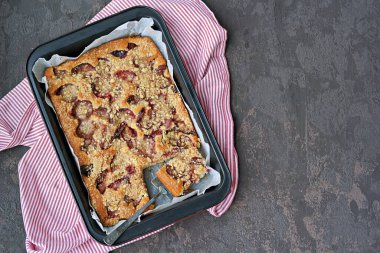 Koyu beton arka planda siyah bir tencerede erik ve shtrezel ile sünger keki. Erikleri hasat et. Erikli tarifler. Alman yemeği. Üst görünüm, alanı kopyala.
