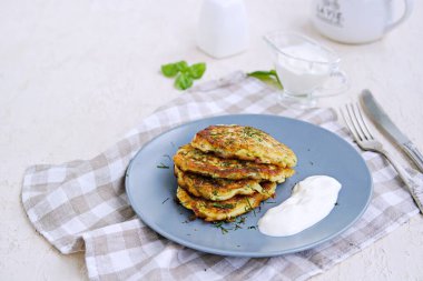 Açık beton arka planda gri bir tabakta beyaz peynirli börek. Ekşi kremayla servis edilmiş. Kabak tarifleri. Seçici odak.