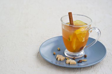 Baharatlı elma şarabı. Alkolik ya da alkolsüz taze filtresiz elma suyundan yapılmış baharatlar, elma dilimleri ve portakallı hafif beton bir arka planda cam bardak. Boşluğu kopyala.