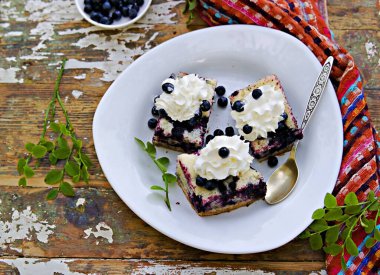 Dilimlenmiş yaban mersinli kek, beyaz bir tabakta gri beton arka planda kremayla süslenmiş. Böğürtlenli kek. Mevsimlik tarifler. 