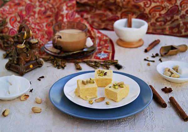 ピスタチオ アーモンド カルダモンを入れたインドのお菓子は 薄いコンクリートの背景に白いプレートの上に マサラティー付き インドの伝統菓子 — ストック写真
