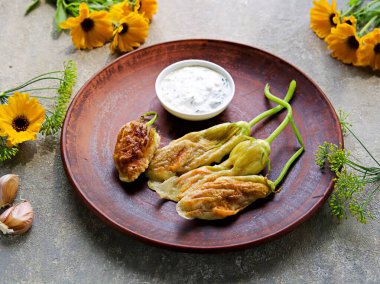 Sıcak aperatif, bol yağda kızartılmış kabak çiçekleri, gri beton arka planda bir tabakta. İtalyan yemeği..
