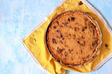 Açık mavi arka planda kuru erikli bir kabak turtası. Üst görünüm, alanı kopyala.