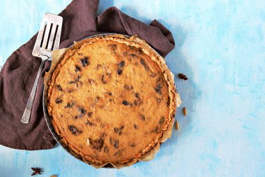Açık mavi arka planda kuru erikli bir kabak turtası. Üst görünüm, alanı kopyala.