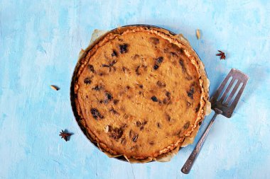 Açık mavi arka planda kuru erikli bir kabak turtası. Üst görünüm, alanı kopyala.
