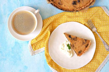 Açık mavi arka planda beyaz bir tabakta kuru erikli balkabağı turtası. Üst görünüm