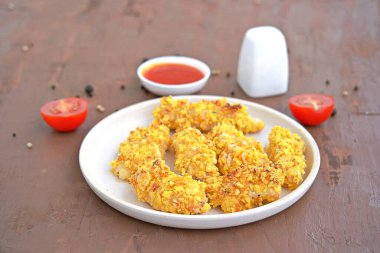 Mısır gevreğinde çıtır tavuk şeritleri ve beyaz tabakta parmesan peyniri. Seçici odaklanma. Amerikan mutfağı..