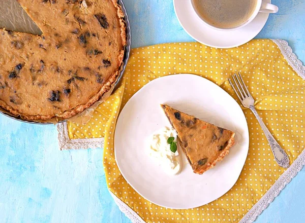 Açık mavi arka planda beyaz bir tabakta kuru erikli balkabağı turtası. Üst görünüm