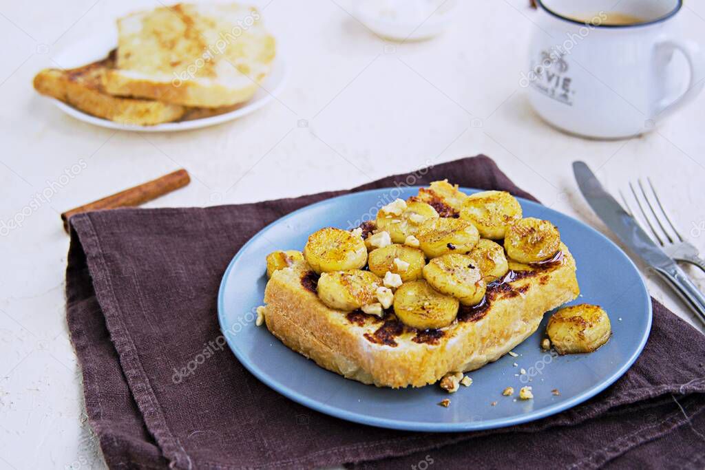 Breakfast, french toasts with banana, walnuts and honey on a gray plate on a light concrete background. French cuisine