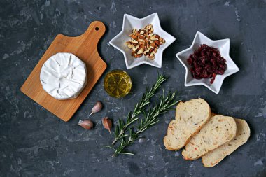 Pişirilmiş camembert peyniri, kurutulmuş kızılcık, taze biberiye, zeytin yağı, sarımsak, ceviz, tost için beyaz ekmek. Üst görünüm, alanı kopyala.