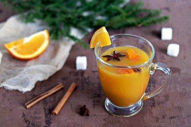 Kahverengi bir arka planda, cam bardakta portakal ve tarçın ile sıcak deniz karabatanı çayı..