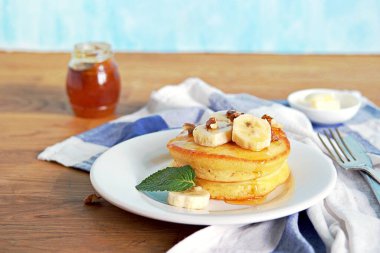 Mısır unu krepleri beyaz tabakta. Muz, ceviz, bal ya da akçaağaç şurubuyla servis edilir..