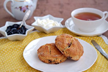 Geleneksel İngiliz çörekleri, beyaz tabakta kurutulmuş yaban mersini. Reçel ve krema ile servis edilir..