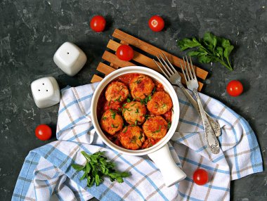 Beyaz seramik tavada koyu beton zemin üzerinde domates soslu balık köftesi. Üst Manzara. Deniz ürünleri..