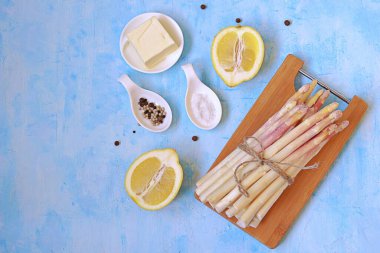 Açık mavi beton arka planda kuşkonmaz pişirmek için gerekli malzemeler. Üst görünüm, alanı kopyala.