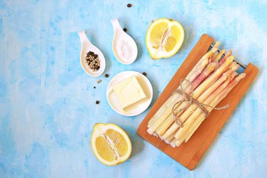 Açık mavi beton arka planda kuşkonmaz pişirmek için gerekli malzemeler. Üst görünüm, alanı kopyala.