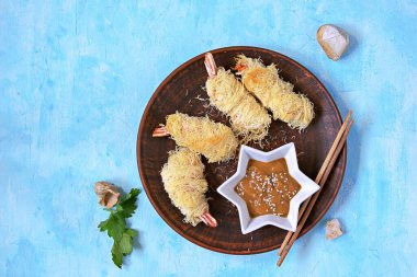 Atıştırmalık ya da öğle yemeği, hamur hamurunda büyük bir karides, kilden bir tabakta Kataify. Fıstık sosuyla servis edilmiş. Asya mutfağı. Üst görünüm, alanı kopyala.